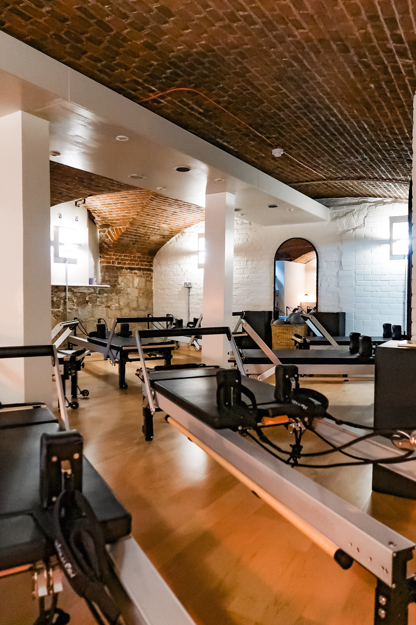 Vaulted basement with wooden floors and reformer pilates machines
